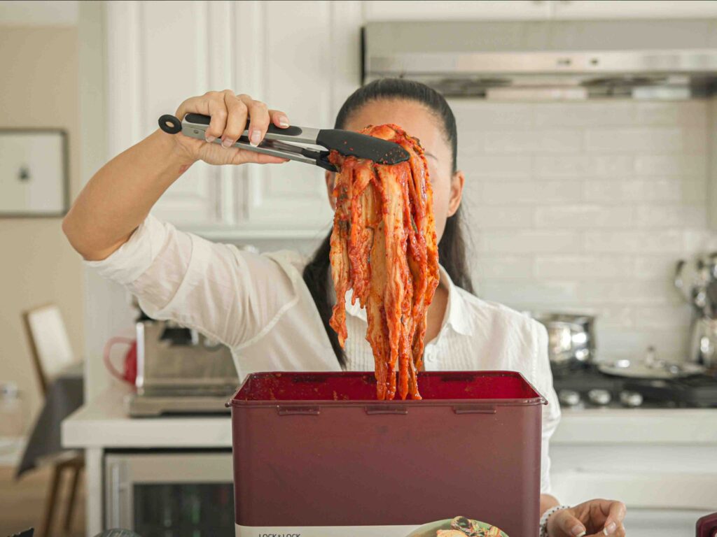 Pulling kimchi out of kimchi container with tongs