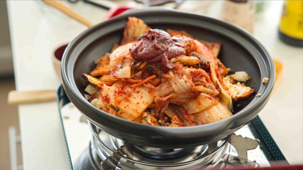 kimchi gochujang and vegetables prepped for kimchi jjigae in pot