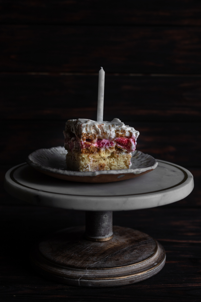 birthday cake slice with unlit candle on cake stand