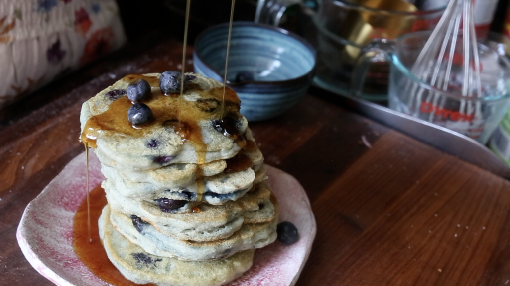 Pancakes drizzled with maple syrup and garnished with fresh blueberries.