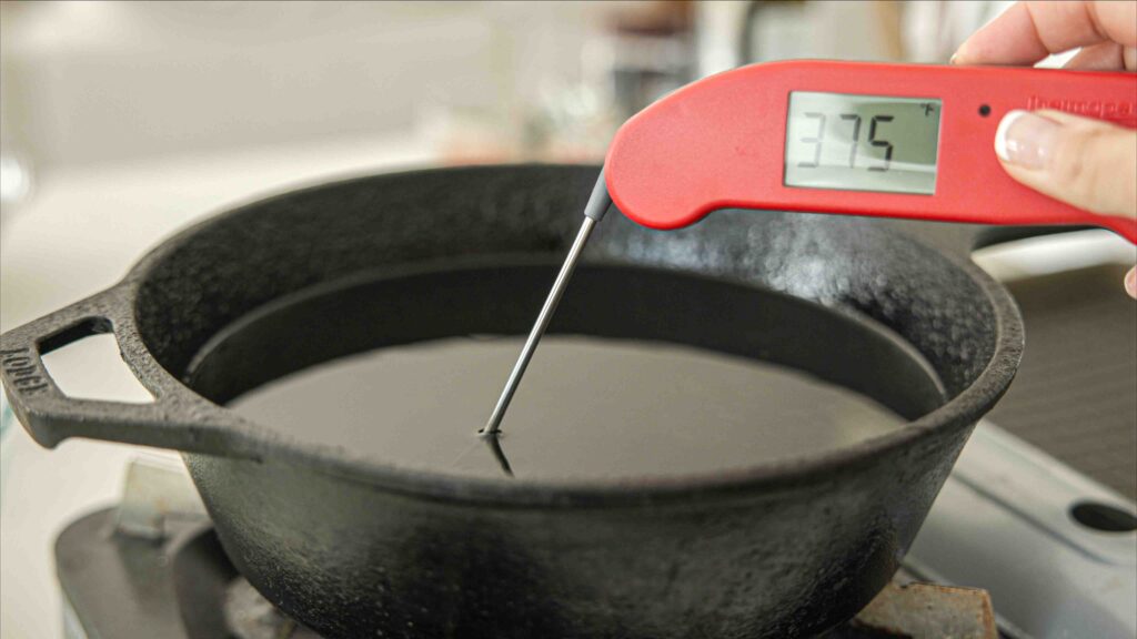 checking temperature of frying oil with thermometer