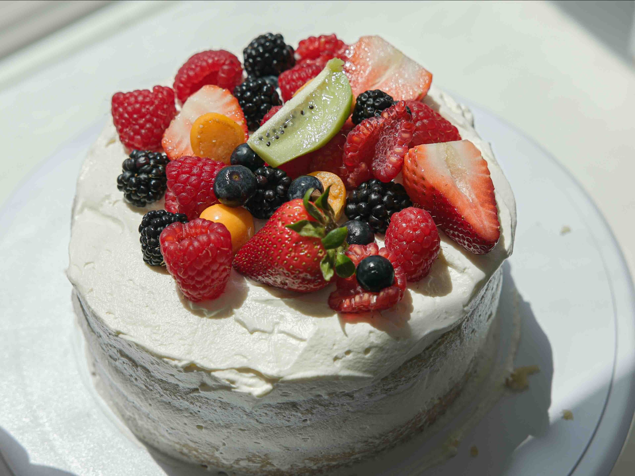 Decorated sponge cake with fruit and whipped cream