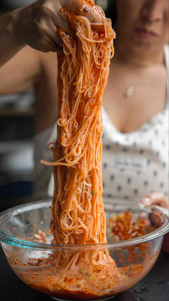 pulling kimchi noodles out of bowl to serve