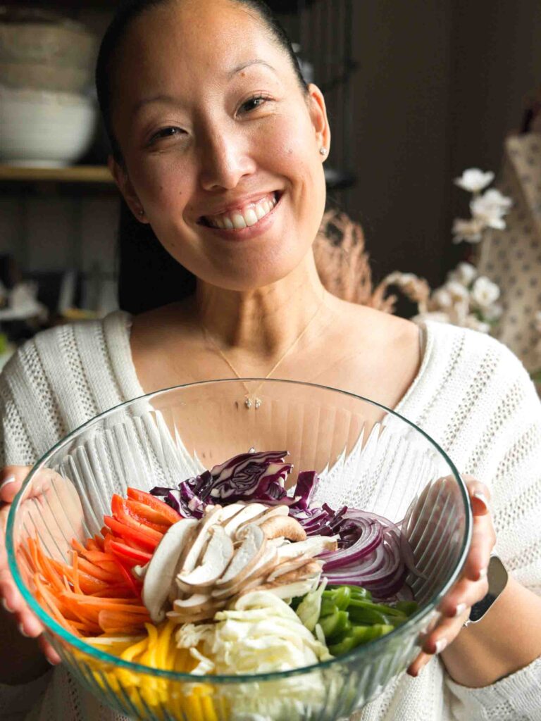 woman holding bowl of julienned vegetables for vegan japchae