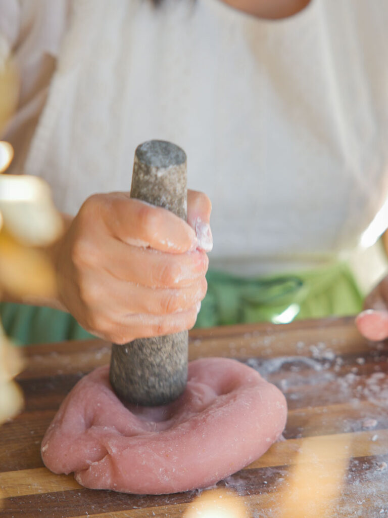 beating pink mochi dough with pestle