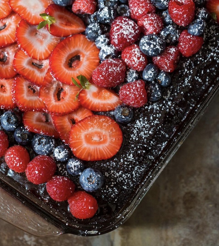 What Being American Means To Me. Cover picture of a cake with Strawberries, Blueberries, and a dusting of powdered sugar color on top.