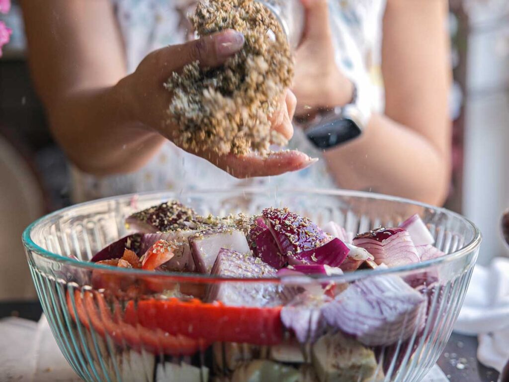 adding-dried-oregano-to-bowl-of-vegetables