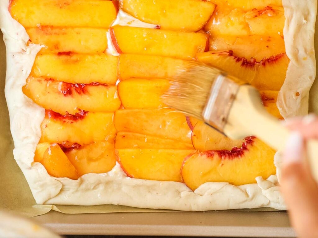 brushing-glaze-on-peaches-for-peach-galette