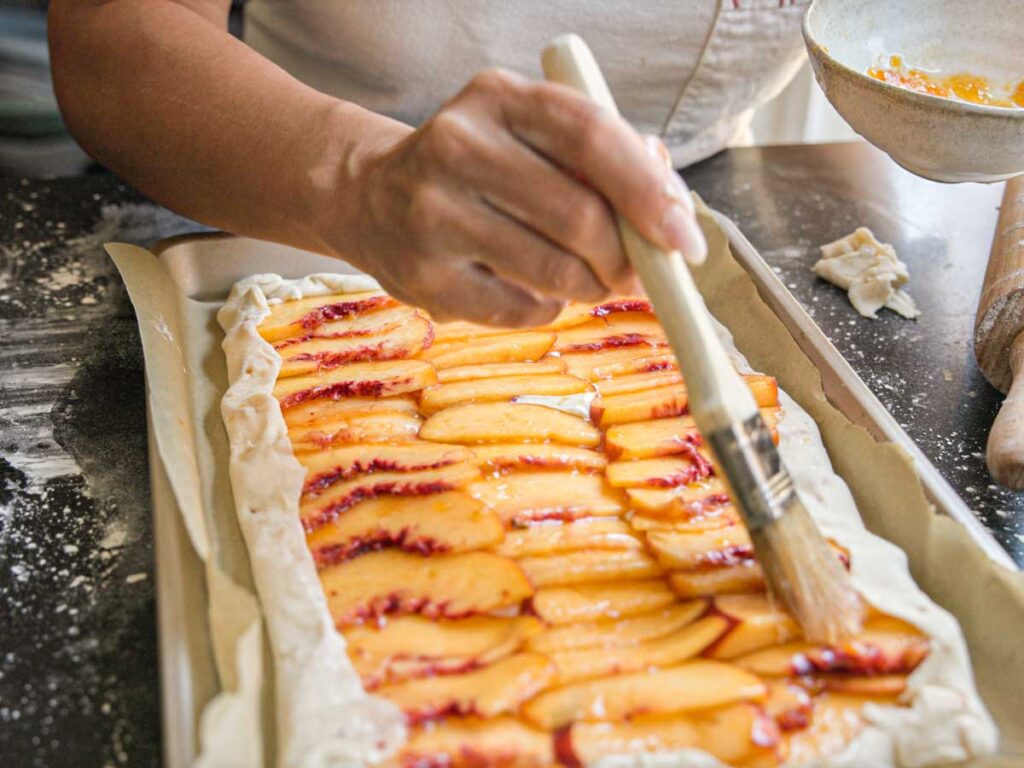 brushing-peaches-with-glaze-for-peach-galette