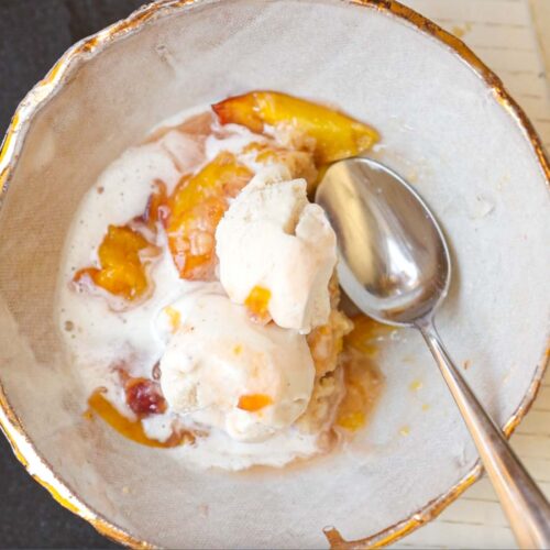 close-up-of-peach-cobbler-piece-with-ice-cream-and-spoon