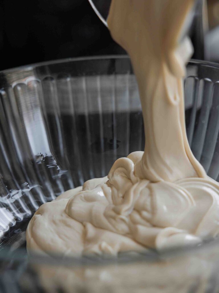 pouring-mascarpone-and-biscoff-buttercream-into-large-bowl-