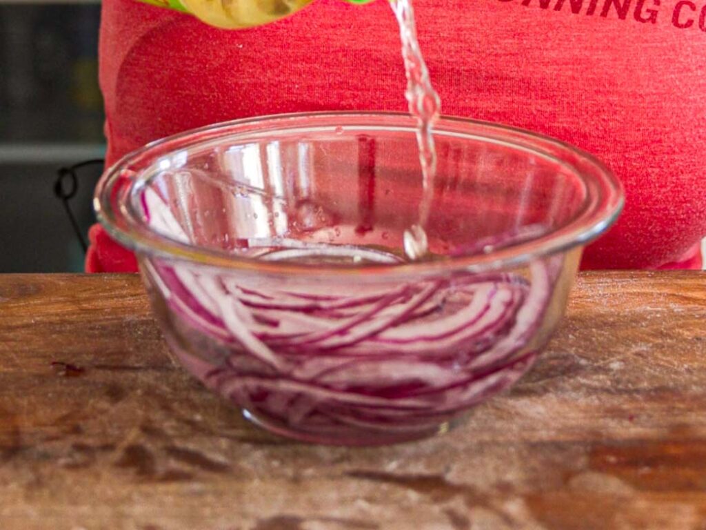 pouring-vinegar-into-bowl-or-sliced-red-onions