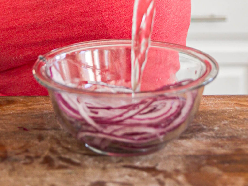 pouring-water-into-bowl-or-sliced-red-onions.