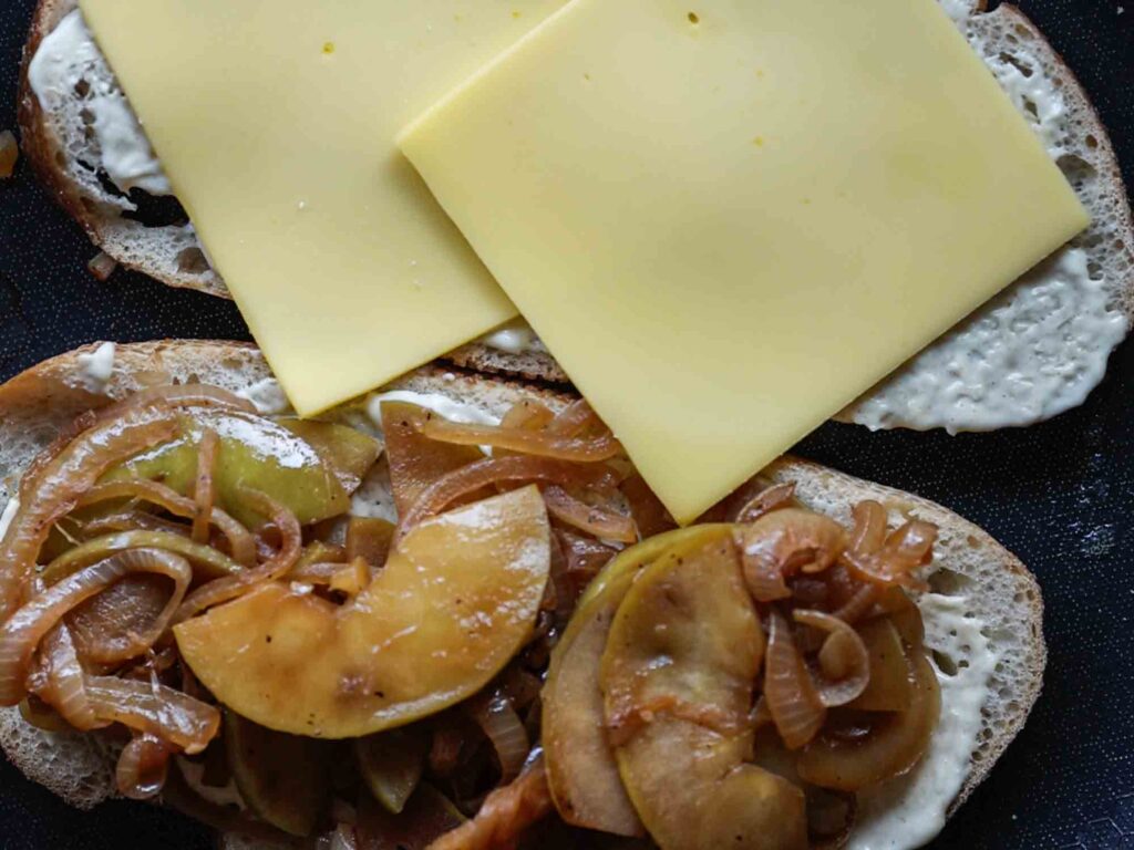 adding provolone cheese slices to bread on pan