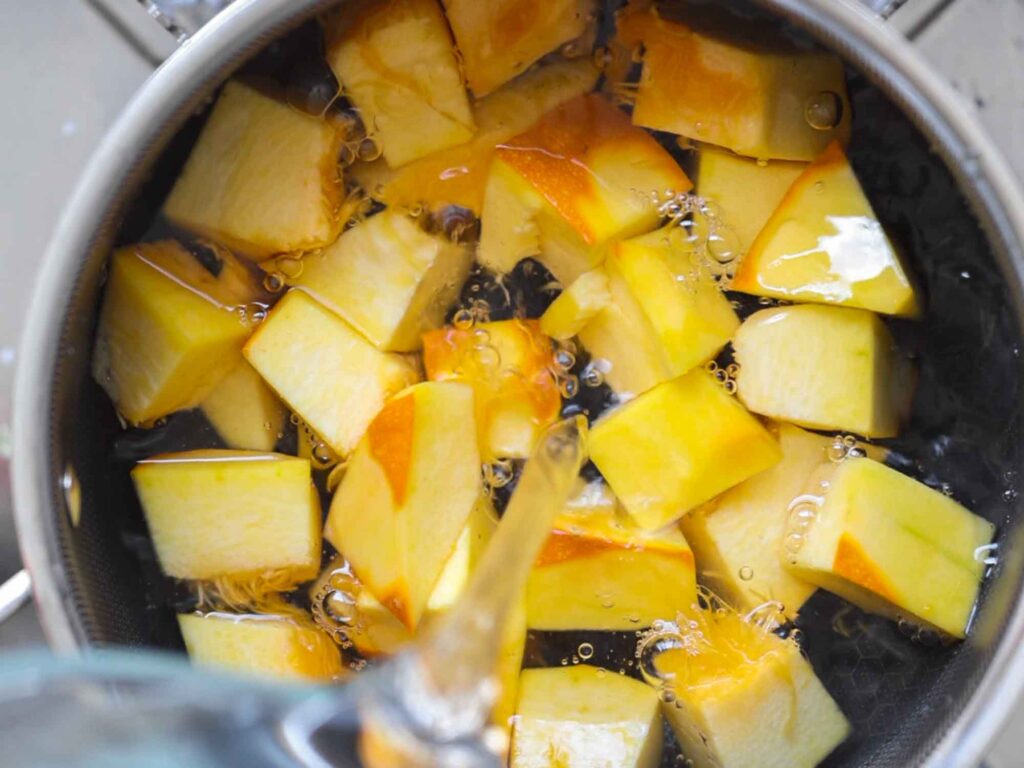 adding water to pumpkin cubes in pot