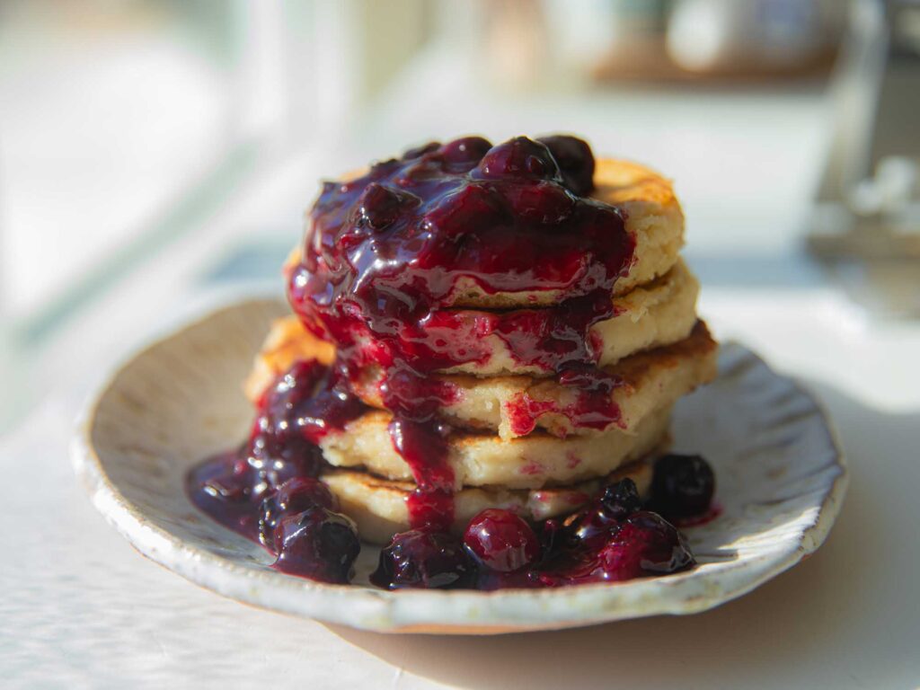 side view of vegan lemon ricotta pancakes with blueberry sauce