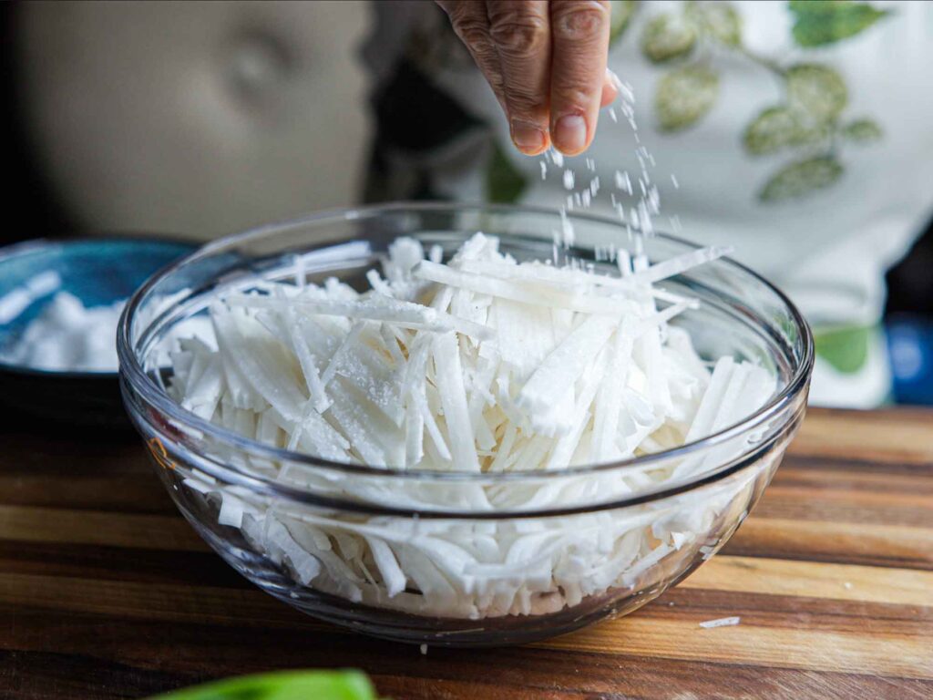 adding sea salt to julienned radish