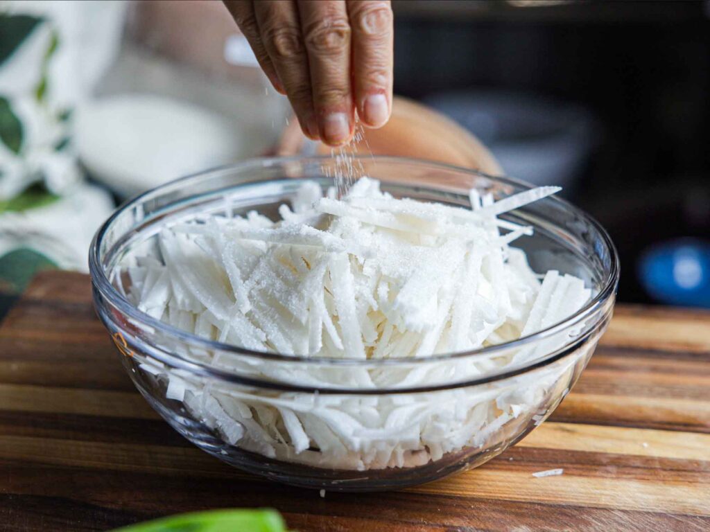 adding sugar to julienned radish