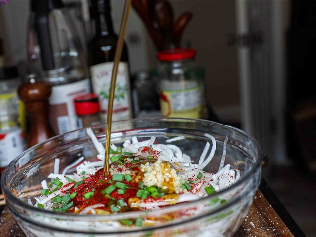 adding plum syrup to julienned radish