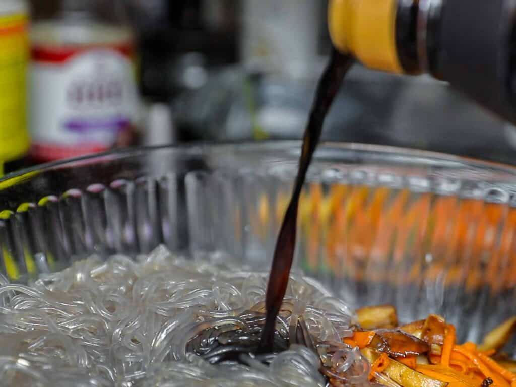 adding soy sauce to japchae