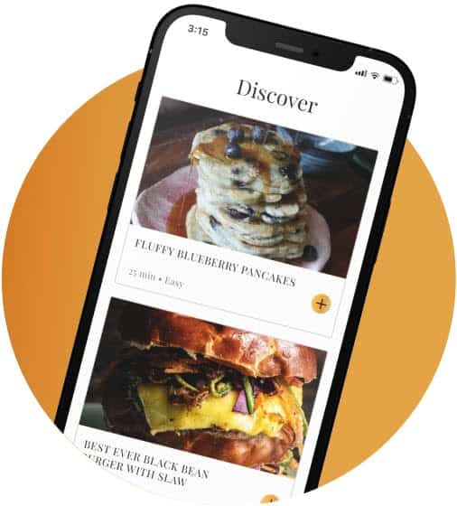 A smartphone displaying a recipe app screen features the Discover section with enticing photos of fluffy blueberry pancakes and a black bean burger with slaw. Perfect for any 2024 Holiday Gift Guide, the app even includes Korean Vegan options to delight all culinary enthusiasts.