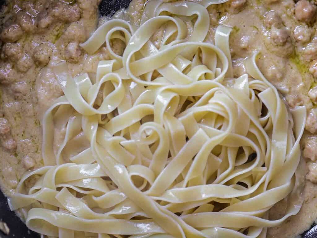 Close-up of fettuccine pasta with a creamy sauce and chickpeas. The pasta is cooked and coated evenly with the sauce, creating a rich and appetizing texture.