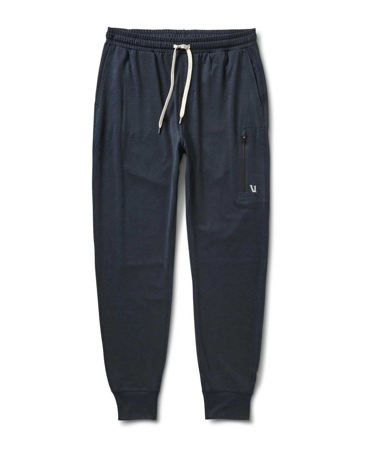 Dark blue jogger pants with an elastic waistband, white drawstring, and side pockets. One pocket features a zipper and a small embroidered logo. The Korean vegan style, with cuffed ankles, is pictured against a white background.