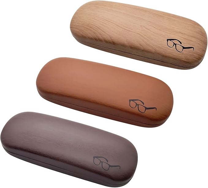 Three eyeglass cases in wood-inspired designs are displayed, perfect for the 2024 Holiday Gift Guide. The oval-shaped cases come in light brown, medium brown, and dark brown shades, each featuring a simple black eyeglasses icon on top.