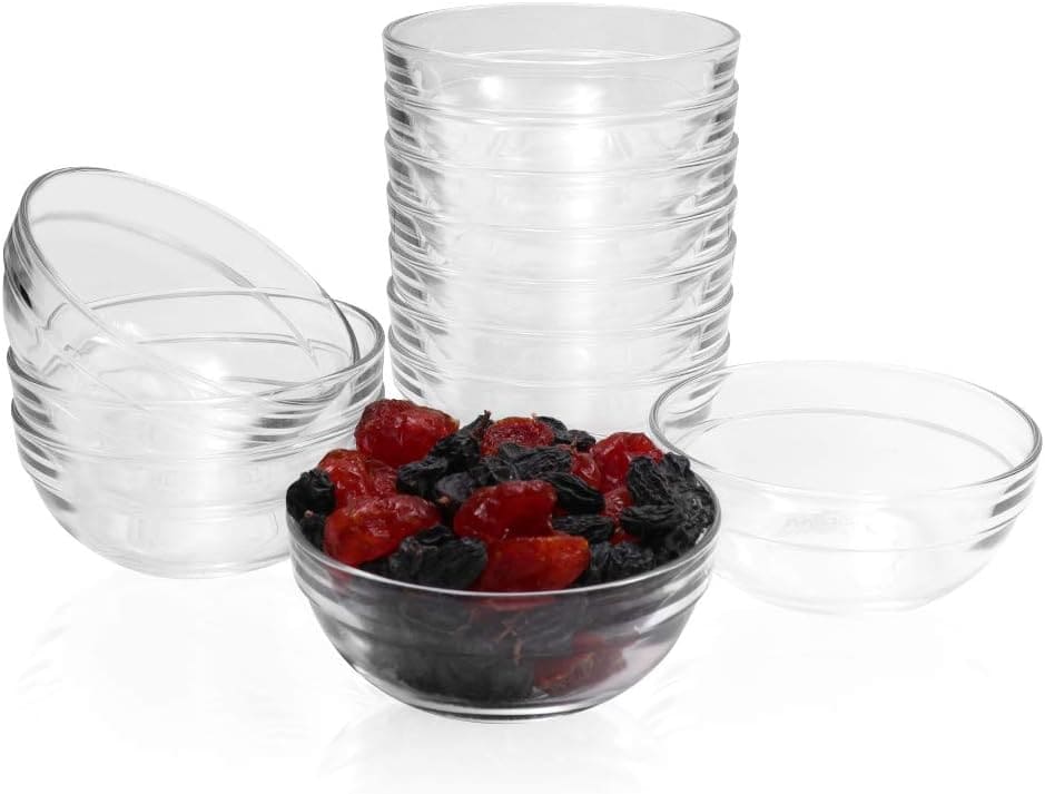 A set of seven clear glass bowls, six stacked neatly while one displays vibrant red and black dried fruits. With their simple design and ridged exterior, they make an elegant addition to any table. 