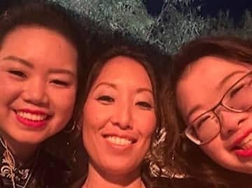 Mental toughness: "Shifting the line" of your distress tolerance. 6 Three women smile and take a close-up selfie outdoors at night. They appear happy, with two wearing bright lipstick and one in glasses. Trees and dim lighting are visible in the background.