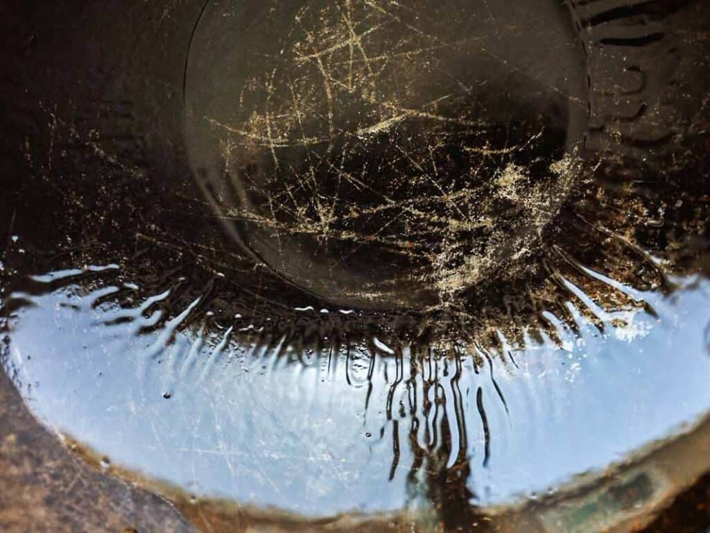 Easy & Healthy Lo Mein Vegan Recipe: Done in Minutes. 25 A close-up of the scratched bottom of a metal pan, with oil and reflecting light, creating abstract patterns and textures.