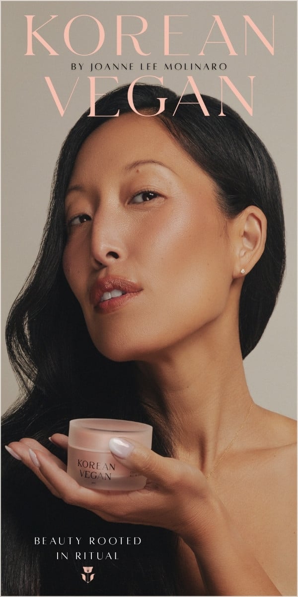 Joanne holds a small jar labeled Korean Vegan near her face. The text reads: KOREAN VEGAN by Joanne Lee Molinaro and Beauty Rooted in Ritual.