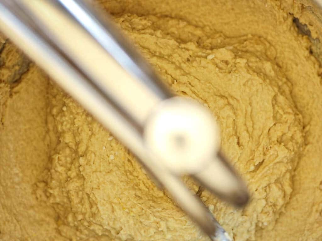 Easy Cherry Brioche Sweet Roll - Vegan Pastry. 23 Close-up of dough in a mixing bowl with a metal ice cream scoop placed on top, ready for scooping. The dough appears smooth and well-mixed.