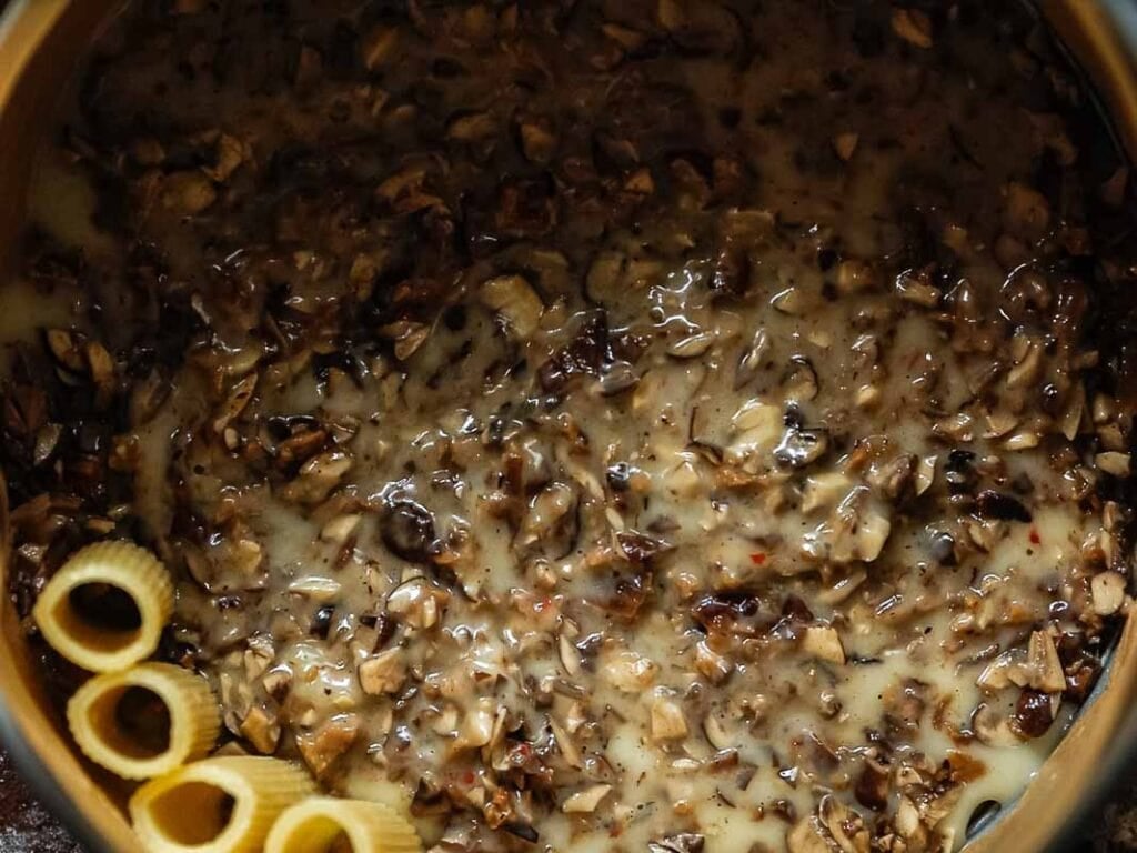 mushroom béchamel and the beginning of rigatoni noodles added to springform pan.