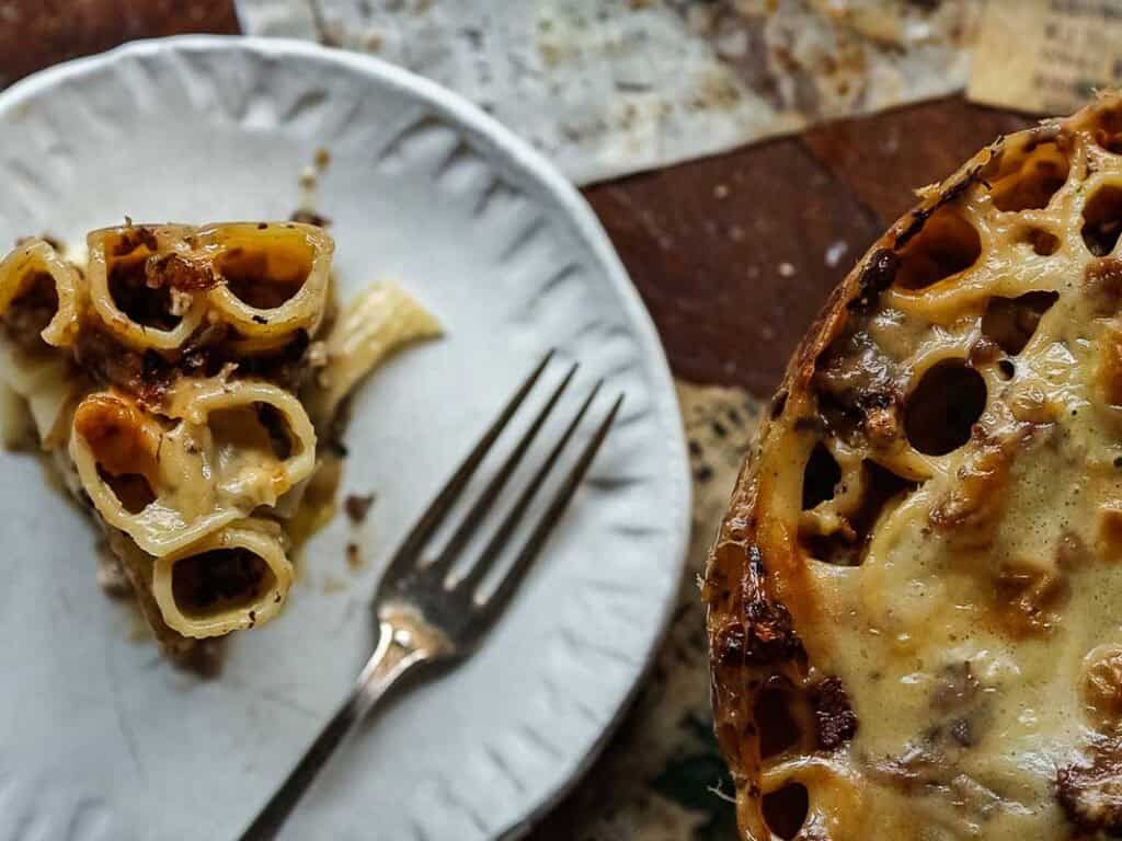 top down view of mushroom rigatoni pie slice on white plate with fork.