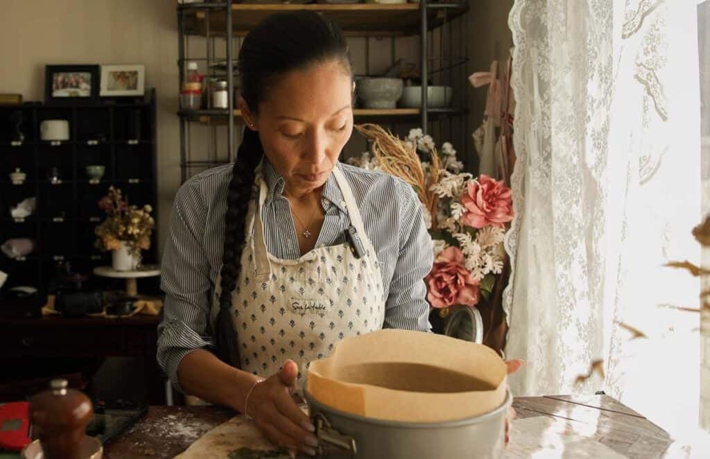 a woman holding springform pan lined with parchment paper.