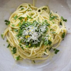 8-ingredient Easy and Delicious Lemon Pepper Pasta. 19 A bowl of Lemon Pepper Pasta topped with grated cheese, chopped fresh parsley, and lemon zest. The delicious pasta is lightly coated in olive oil and arranged in a swirl on a white plate.