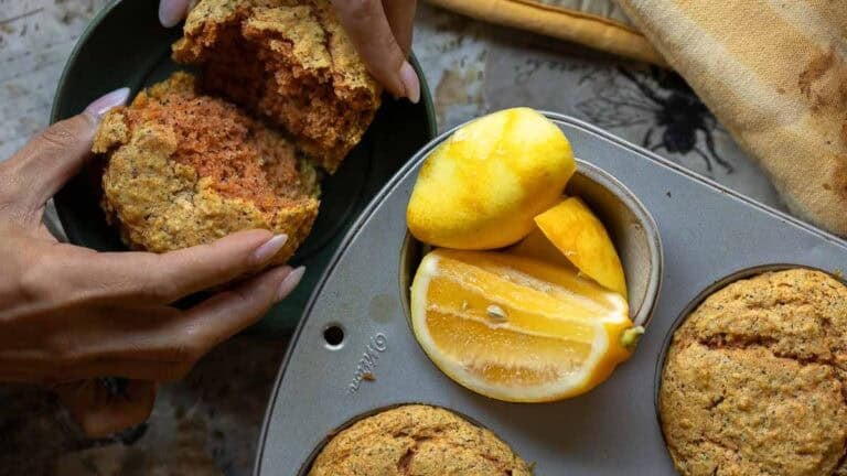 vegan lemon poppyseed muffins as a woman splits one in half.