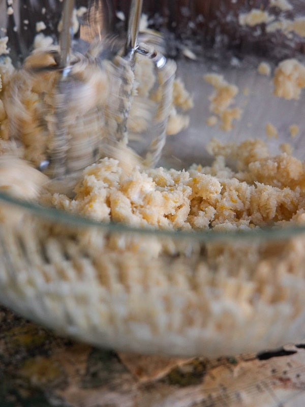 Delicious and Easy Vegan Lemon Poppyseed Muffins. 10 A close-up of an electric hand mixer blending butter and sugar in a glass bowl for vegan lemon poppyseed muffins, creating a creamy texture. The motion of the beaters is blurred, showing movement.