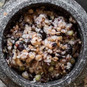 A close-up of Korean multigrain rice, or Japgokbap, featuring gut healthy cooked grains and beans in a stone bowl. The mix appears slightly sticky with an appealing blend of light and dark colors.
