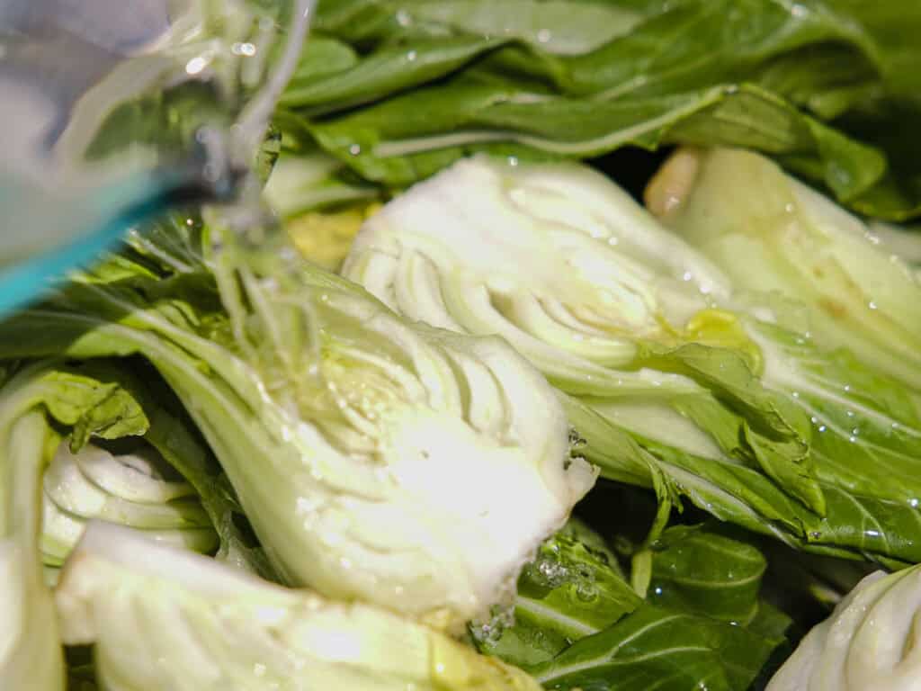 BEST Baby Bok Choy Kimchi Recipe - Easy & Delicious 25 Close-up of fresh bok choy being washed with running water, highlighting green leaves and white stems—perfectly prepared for making homemade bok choy kimchi.