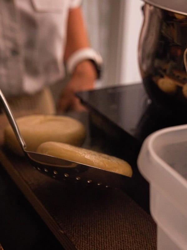 How to Make Delicious NY Style Bagels - Step by Step Guide. 64 A person uses a slotted spatula to lift a boiled potato from a cutting board near a pot and a container, much like preparing ny style bagels before they’re baked to perfection.