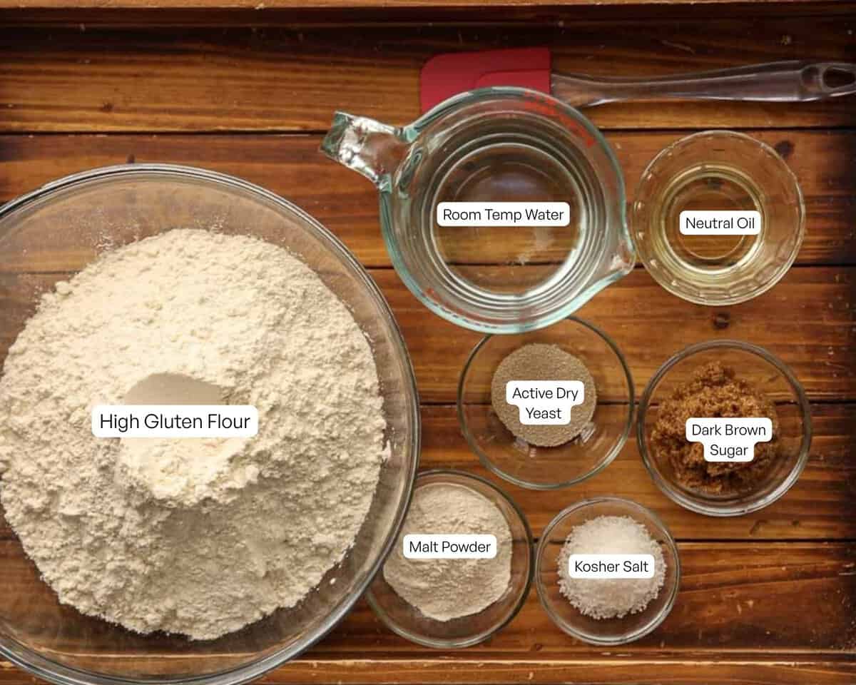 How to Make Delicious NY Style Bagels - Step by Step Guide. 13 A wooden table with bowls of high gluten flour, malt powder, active dry yeast, kosher salt, dark brown sugar—classic ingredients for authentic NY style bagels—as well as cups of room temp water and neutral oil, all labeled.