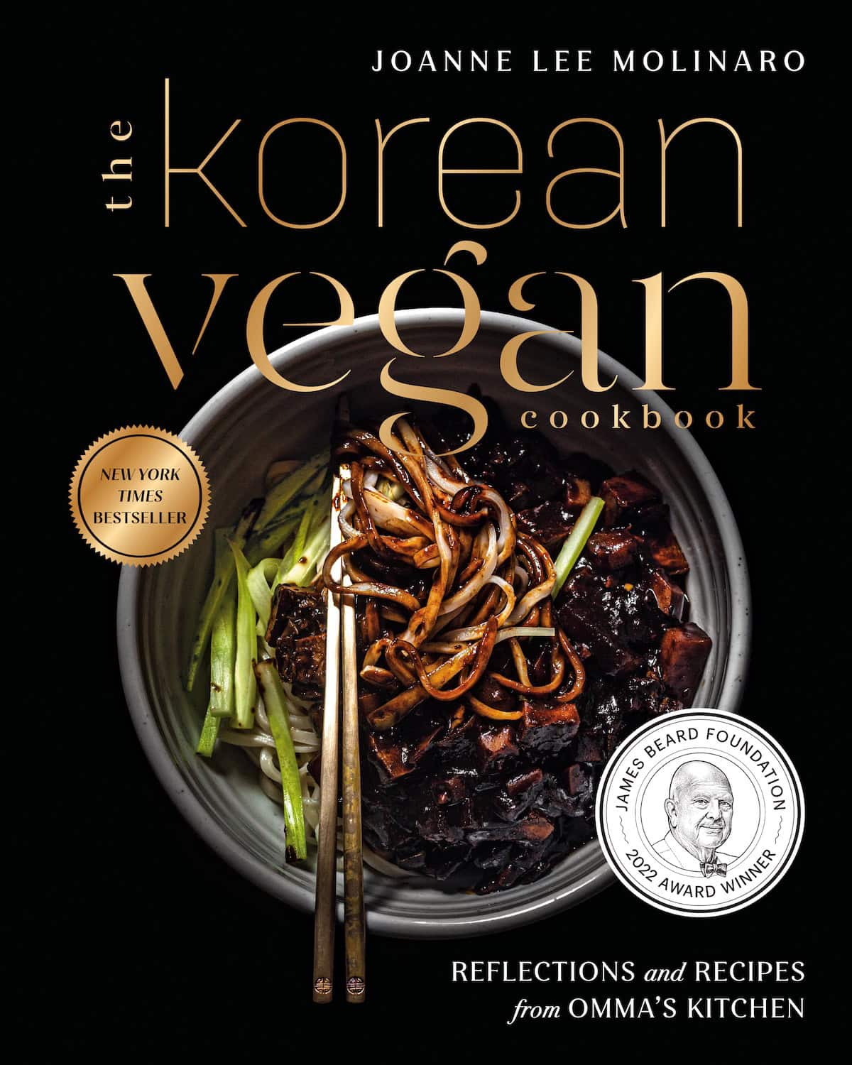Home 17 Cover of The Korean Vegan Cookbook by Joanne Lee Molinaro, showcasing the vibrant appeal of Korean Vegan cuisine with a bowl of noodles, green vegetables, chopsticks, award seals, and elegant gold text set against a sleek black background.